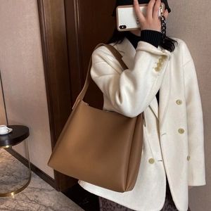 Brown leather tote bag for women shown as a shoulder bag with minimalist design