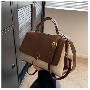 Detail of color-block tote bag with adjustable strap and golden circular buckle