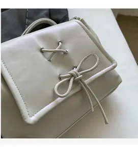 Dettaglio borsa a mano bianca in ecopelle con decorazione a fiocco e lacci incrociati