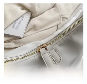 Detailed close-up of premium gold-toned zipper on white faux leather shoulder bag