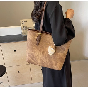 Detailed macro view of vintage brown tote bag with marble texture and plush charm