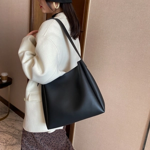 Minimalist large black matte leather tote bag shown on a model for daily commute style