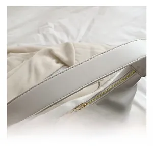 Detail view of white leather shoulder bag featuring wide strap and premium gold zipper