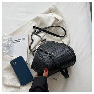 Close-up of black woven leather handbag texture with elegant metal chain strap detail