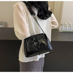 Dettaglio della borsa a tracolla nera con fiocco alla moda e tracolla a catena in metallo