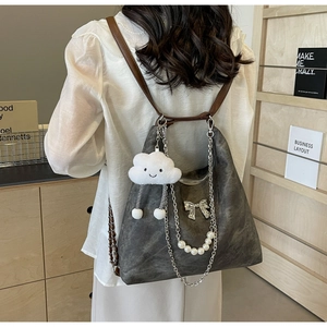 Close-up of charcoal grey leather tote bag with pearl chains and cloud plush charm