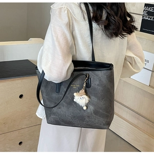 Detail of dark grey tote bag with soft texture and cute white plush monster charm