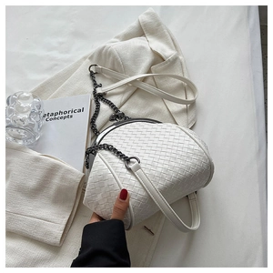 Close-up of white woven shell crossbody bag featuring a metal chain and leather strap