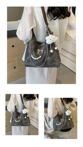 Close-up of dark grey tote bag with brown straps, silver bow and white cloud charm