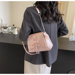 Vista posteriore di una borsa a tracolla rosa chiaro con fiocco su un blazer grigio