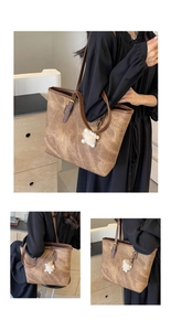 Detailed view of brown vintage textured tote bag with golden lettering and plush charm