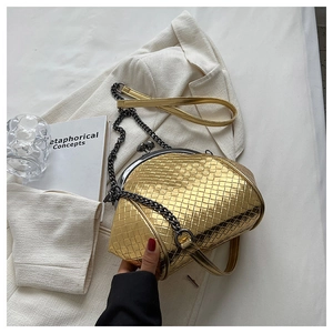 Detail view of a golden woven texture handbag with metal chain and vintage clasp