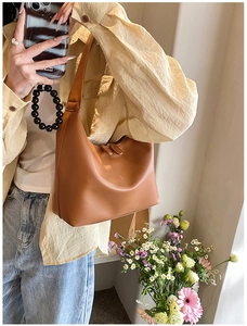 Close-up of a brown leather hobo shoulder bag featuring a sleek double zipper top closure