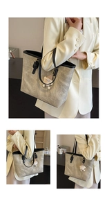 Detail view of large grey tote bag with marble texture and monster charm accessory