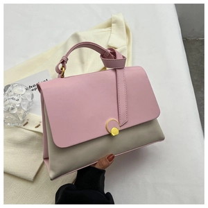 Pink and beige contrast faux leather handbag with gold buckle in an elegant setting