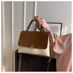 Elegant minimalist bicolor top-handle bag in cream and brown leather with gold ring buckle