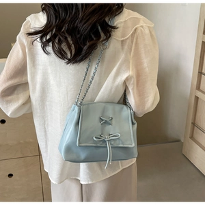 Borsa tote celeste alla moda con fiocco e tracolla a catena indossata da modella