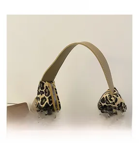 Detail of the leopard print woven fabric and khaki faux leather strap on tote bag