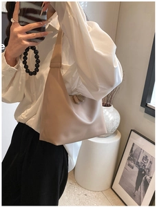 Close-up of minimalist beige hobo bag with smooth texture and double zipper detail