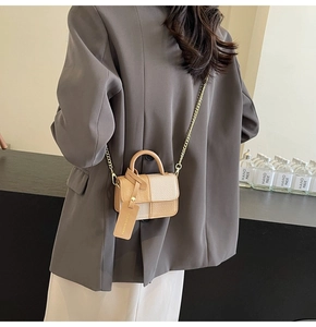 Detail of two-tone beige handbag with woven texture flap and golden chain strap