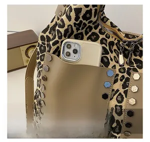 Detail view of leopard print tote bag with khaki leather front pocket and silver rivets