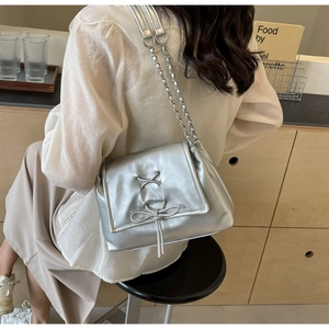 Dettaglio della borsa tote argento metallizzato con fiocco e tracolla a catena