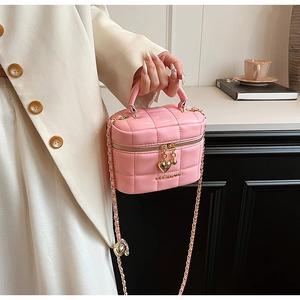 Détail d'un sac matelassé rose avec chaîne, logo doré et fermeture éclair en forme de cœur