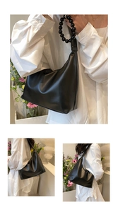 Detail of black faux leather hobo bag featuring decorative large bead handle accents
