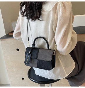 Detail of grey and black checkerboard crossbody bag with decorative fashion brand tag