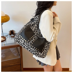 Leopard print canvas tote bag with black leather front pockets and metal rivet details