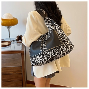 Detailed view of leopard print tote bag with black leather trim and silver metal studs