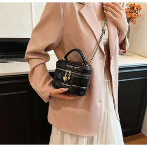 Détail du sac matelassé en cuir noir avec chaîne dorée et pendentifs en forme de cœur