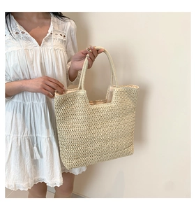 Gros plan du sac cabas en paille tressée crème avec texture nid d'abeille et anses solides