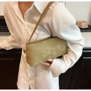 Macro view of moss green matte suede handbag with embossed logo and textured surface