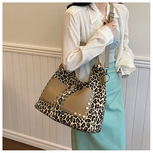 Detailed shot of leopard print tote featuring silver studs and adjustable leather strap