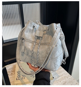 Close-up of silver-grey bucket bag with pleated texture, drawstring and silver chain