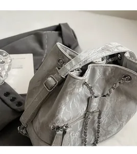 Close-up of silver pleated bucket bag with metallic chain and long smooth shoulder strap