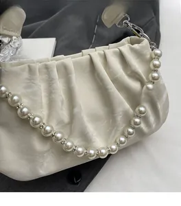 Detail of cream pleated bag with pearl strap and rhinestone spacers for an elegant look