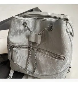 Detail of silver bucket bag featuring metallic crinkled texture and sleek chain drawstring