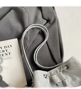 Close-up of shiny pleated silver-grey bucket bag with metal chain and thin shoulder straps