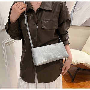 Chic silver-grey shoulder bag with vintage texture shown on a stylish model outfit