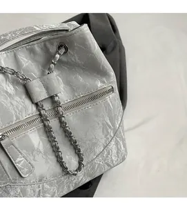 Detail shot of the pleated silver texture and metal chain strap on this bucket bag