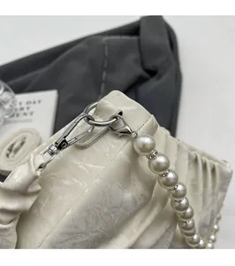Detail of cream pleated handbag with large pearl strap and silver metal buckle