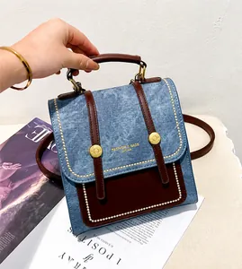 Detail of vintage denim blue and brown leather handbag with metallic rivet accents