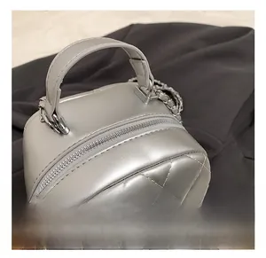 Detail of silver quilted mini backpack featuring a smooth handle and metal zipper