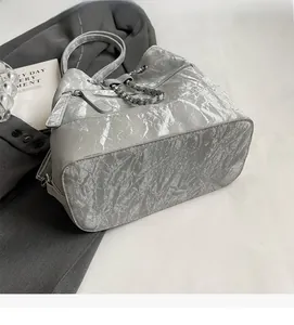 Detail view of silver bucket bag with metallic crinkled texture and chain accent