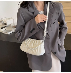 Detail of white pleated cloud bag with elegant pearl chain and leather shoulder strap