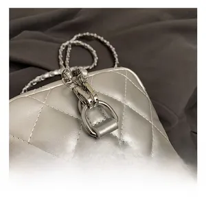Macro shot of silver metal hook and leather chain strap on quilted backpack
