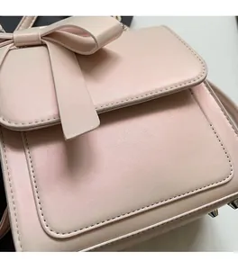 Macro detail of pink leather bag featuring a bow decoration and silver metal base feet