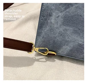 Detail showing the detachable brown leather shoulder strap with gold metal buckle